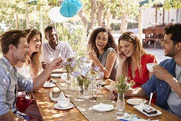 Six young friends dining at a table outdoors