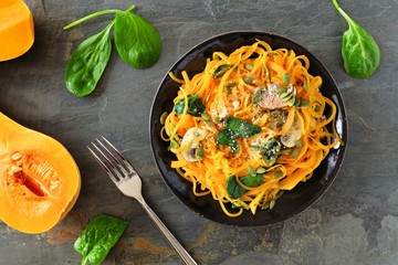 Butternut squash spirilized noodles with spinach and pumpkin seeds on dark slate background,...