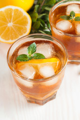 Refreshing citrus lemonade, summer drink. Ice tea with fresh lemon and mint on wooden background. Refreshment beverage concept.