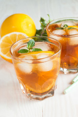Refreshing citrus lemonade, summer drink. Ice tea with fresh lemon and mint on wooden background. Refreshment beverage concept.