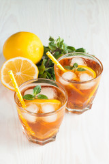 Refreshing citrus lemonade, summer drink. Ice tea with fresh lemon and mint on wooden background. Refreshment beverage concept.