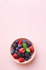 Berry (raspberry, blueberry, blackberry) fruits bowl on a pastel background. Top view. Copy space