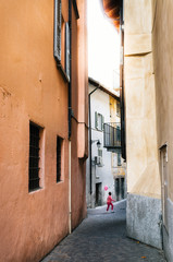 Fototapeta na wymiar Boy in pink clothes holding pink balloon celebrates Breast Cancer Awareness Month in October in narrow Italian street in Chiavenna, Italy