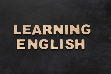 Learning English spelled with wooden letters on black background