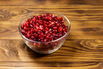 Pomegranate seeds in glass bowl on wooden table