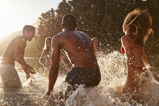 Young adult friends on vacation splashing in a lake