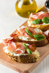 Italian tomato, prosciutto, jamon, ham and cheese bruschetta. Tapas, antipasti with chopped vegetables, herbs and oil on grilled ciabatta and baguette bread.