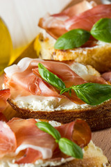 Italian tomato, prosciutto, jamon, ham and cheese bruschetta. Tapas, antipasti with chopped vegetables, herbs and oil on grilled ciabatta and baguette bread.