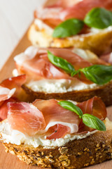 Italian tomato, prosciutto, jamon, ham and cheese bruschetta. Tapas, antipasti with chopped vegetables, herbs and oil on grilled ciabatta and baguette bread.