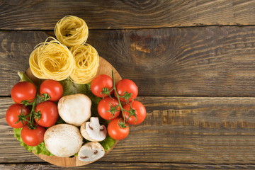 Mushrooms mushrooms, lettuce, tomatoes and spaghetti on wooden table.