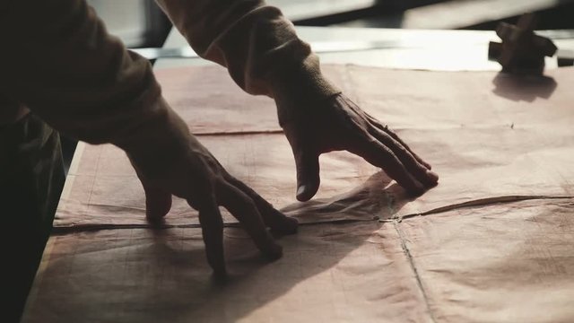 Designer studies archival drawings and old decrepit documents. Man engineer carefully looks at archival documents. Only hands, close up. Men's hands move according to the blueprints.