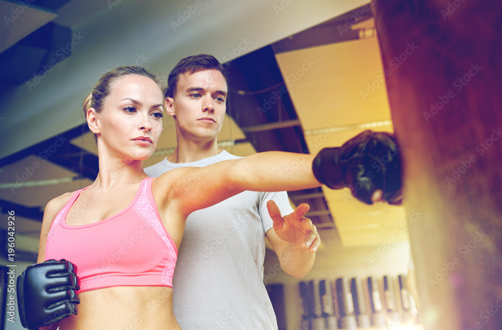 Poster woman with personal trainer boxing in gym