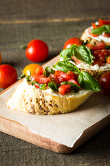 Tomato and cheese fresh made bruschetta. Italian tapas, antipasti with vegetables, herbs and oil on grilled ciabatta and baguette bread.