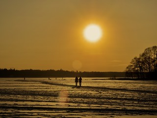 People walking on the frozen sea over the sunsetting sky, Espoo, Finland