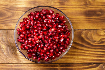 Pomegranate seeds in glass bowl on wooden table
