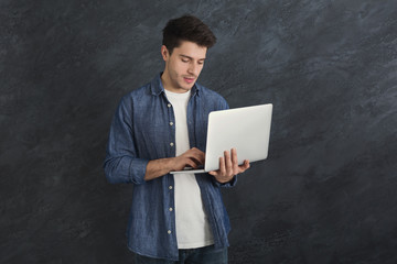 Young serious man using laptop computer