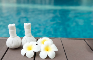 Obraz na płótnie Canvas Thai herbal massage balls on the wooden at swimming pool background.