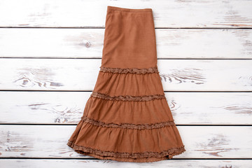 Flat lay brown women dress. Fashionable gown in white wooden desks surface background.