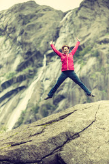 Happy woman jumping on rock in mountains