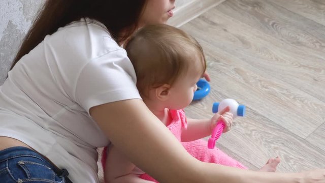 Young mother plays with her little baby in toys.