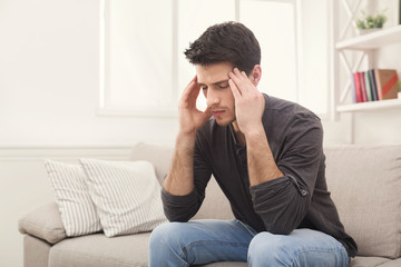 Young man having headache at home