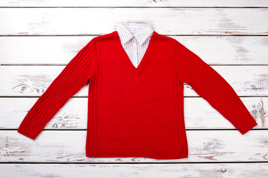 Flat lay red woolen sweater pullover. White wooden background top view.