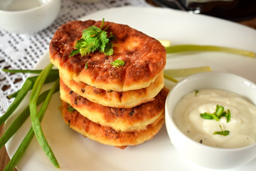 Golden cottage cheese pancakes syrniki and sour cream sauce on a white plate