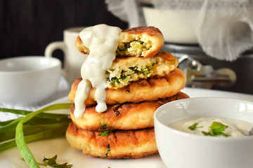Golden cottage cheese pancakes syrniki with sour cream sauce on a white plate