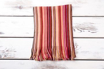 Stylish knotted folded scarf. White wooden desks surface background.