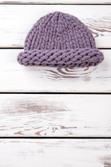 Fototapeta na wymiar Flat lay purple knitted hat. White wooden desks surface background.