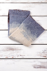 Folded colourful woolen scarf, flat lay. White wooden desks surface background.