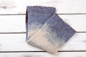 Close up folded woolen scarf. White wooden desks surface background.