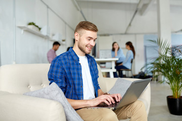 smiling man with laptop working at office