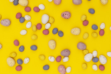 Easter egg candy chocolates on a bright yellow springtime background