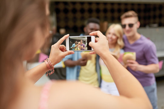 woman photographing friends eating at food truck