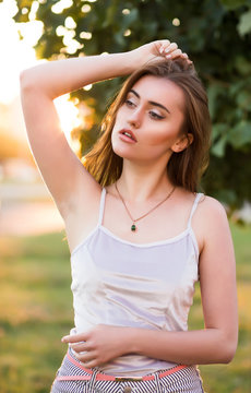 Wonderful brunette woman with perfect skin posing in rays of sun at sunset