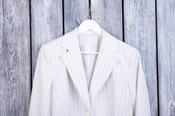 Close up white business jacket on hanger. Dark wooden background. Top view.