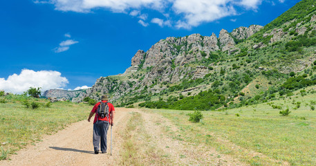 Naklejka premium Lonely hiker on the remote road to Valley of Ghosts in Crimean mountains