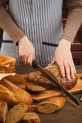 Woman cutting bread on wooden board