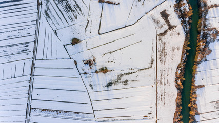 Drop down view of river passing snow covered fields.