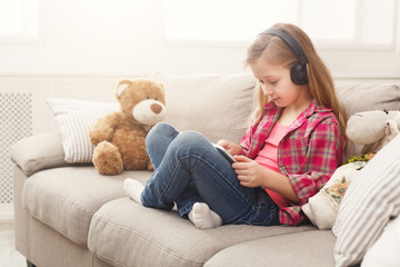 Little girl in headphones with tablet at home