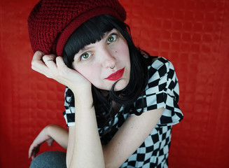 Preciosa mujer joven y pelirroja con actitud en una sesión de fotos en estudio con fondo rojo 