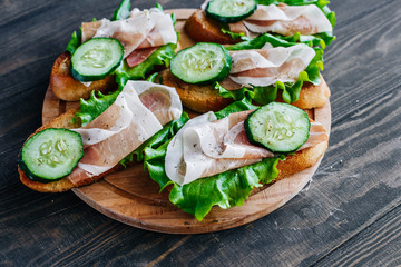 Sandwiches with cucumbers and prosciutto on the board