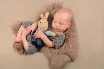 sweet newborn baby slipping with a toy hare knitted rabbit