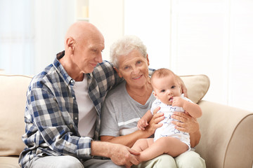 Senior couple with their little grandchild resting at home