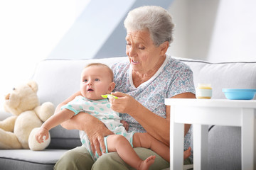 Senior woman feeding her little grandchild at home