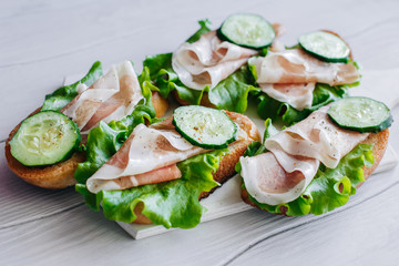 Sandwiches with cucumbers and prosciutto on the board