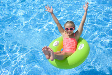 Happy little girl  with  life ring has fun in the swimming pool