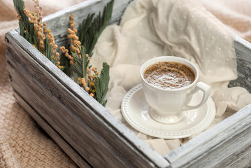 Cup of coffee and a wooden box on a knitted plaid