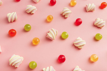 Marshmallows and colourful sweets on pink background